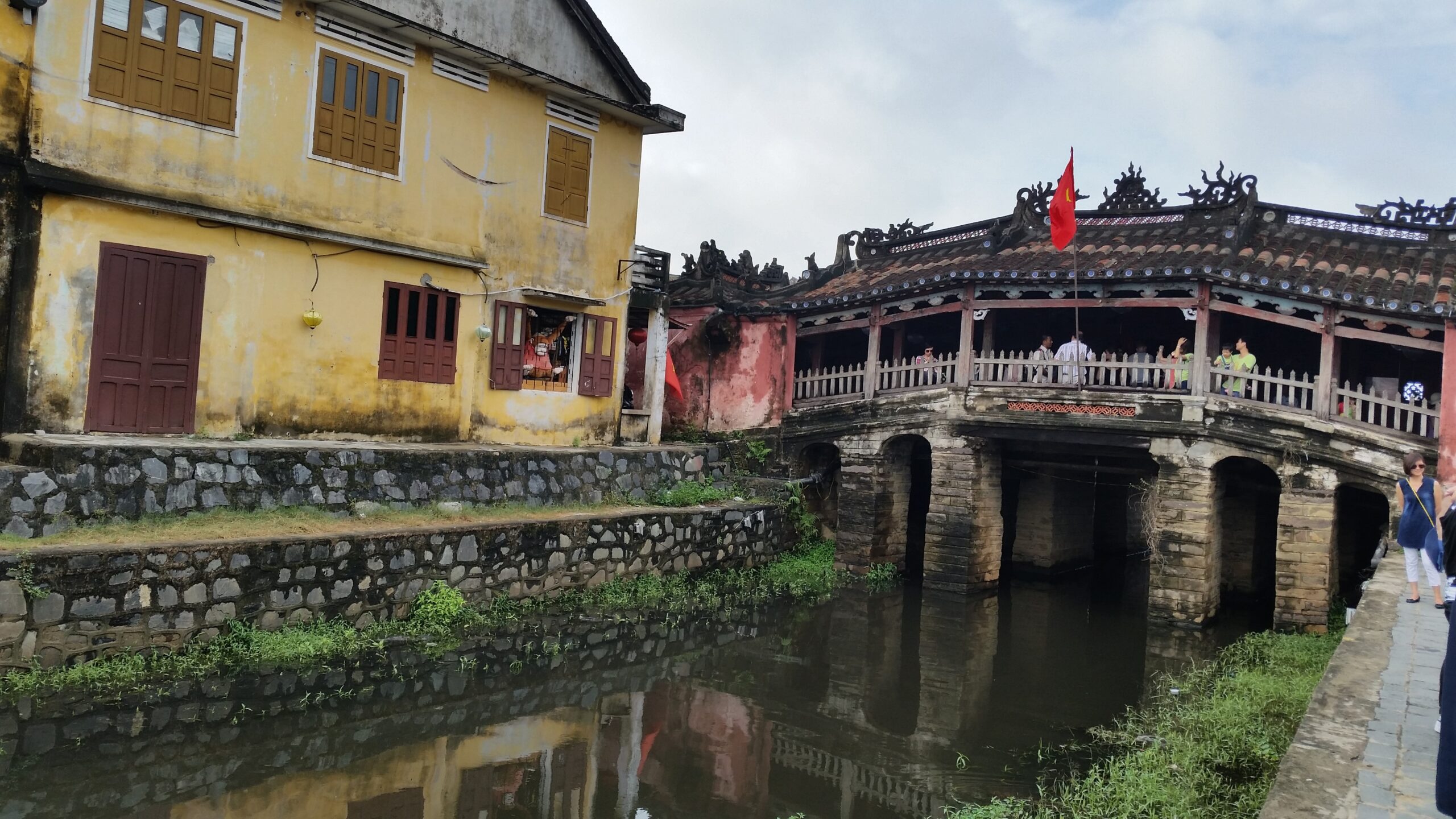 Japanese bridge over canal with yellow building.