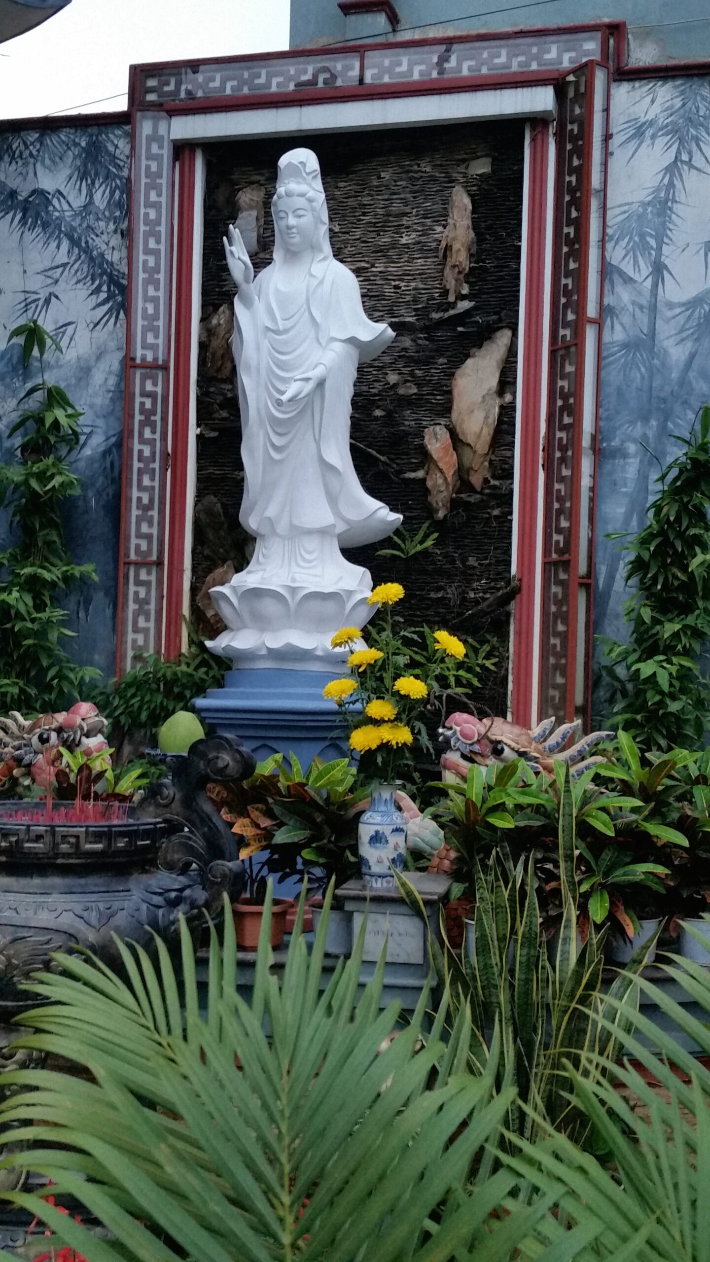 White statue surrounded by flowers and plants.