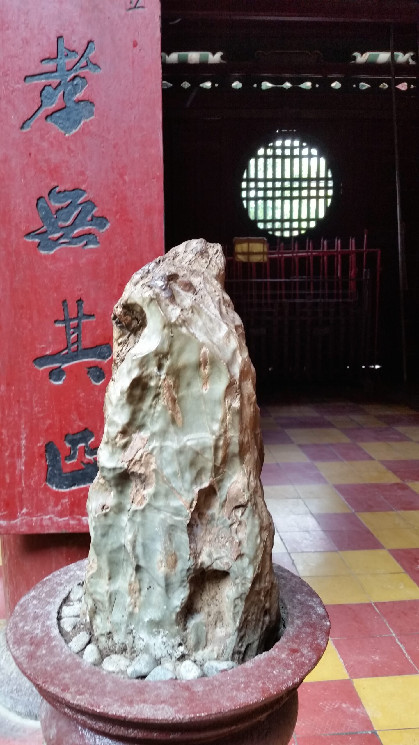 Decorative rock in pot near red pillar.