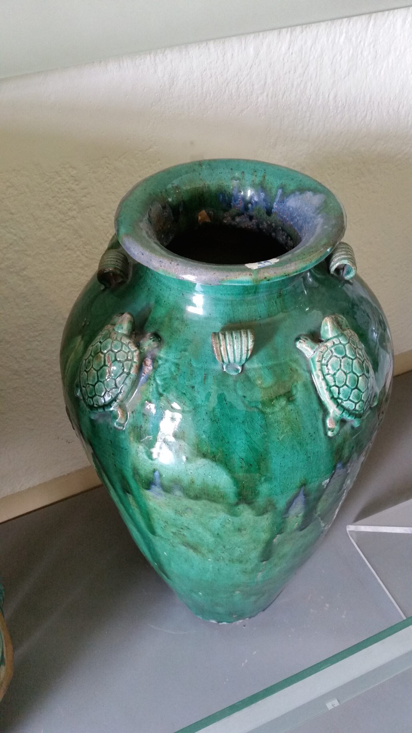 Green ceramic vase with turtle decorations.