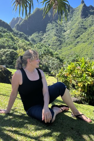 Woman relaxing on grass in lush mountains.