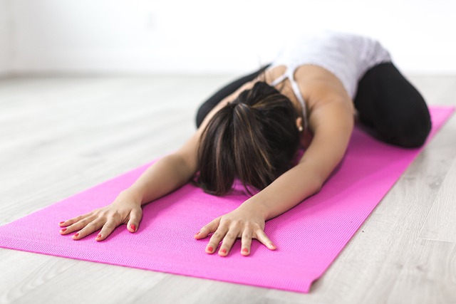 Person practicing yoga on pink mat.