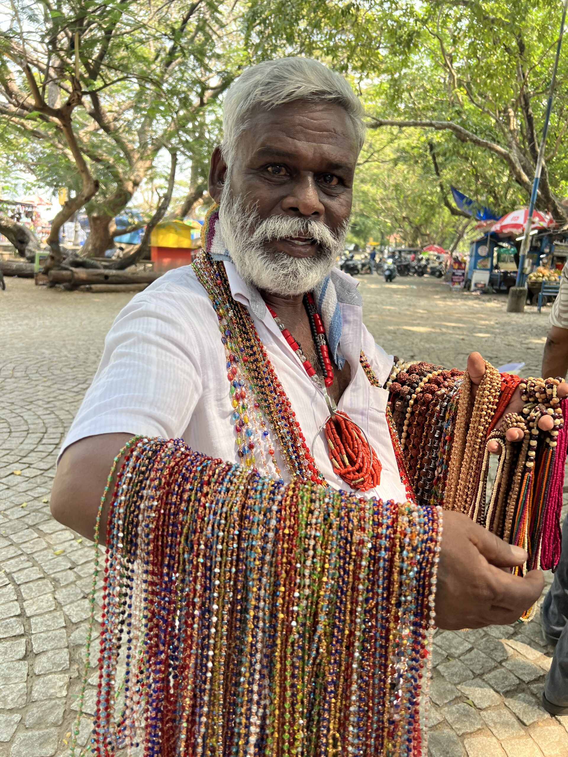 Man selling colorful beaded necklaces outdoors.