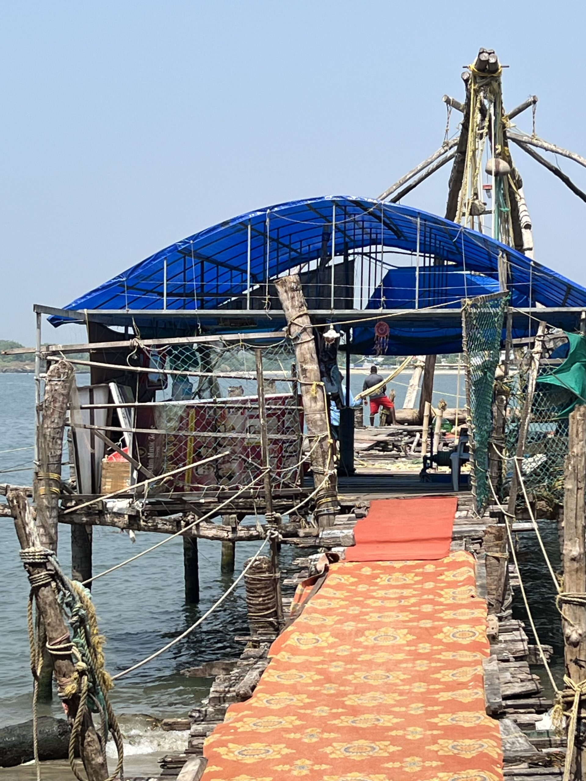 Rustic pier with blue canopy over water.